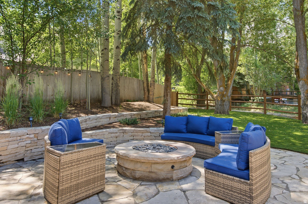 Flagstone patio featuring a built-in stone fire pit, tiered stone retaining walls, and a perimeter fence