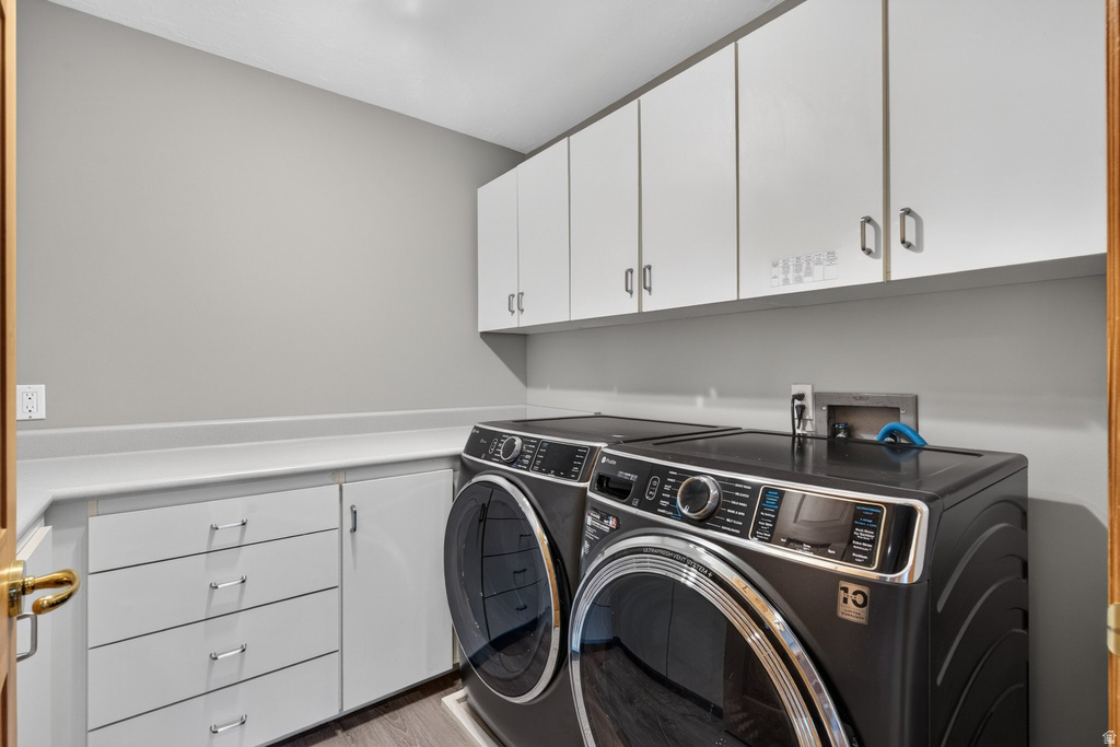 Laundry room featuring white cabinetry, a light-toned countertop, and wood-finish flooring