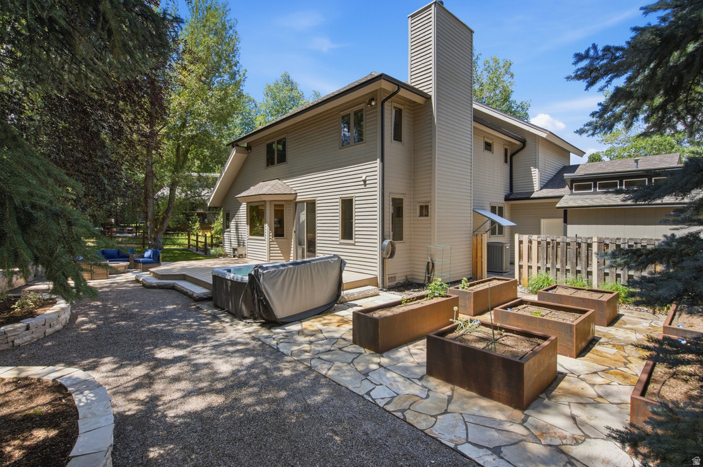 Expansive backyard featuring a hot tub, flagstone patio, gravel pathways, and multiple raised garden beds