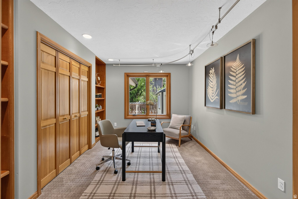Interior room featuring a large window, built-in shelving, track lighting, light grey wall paint, and wood-paneled closet doors