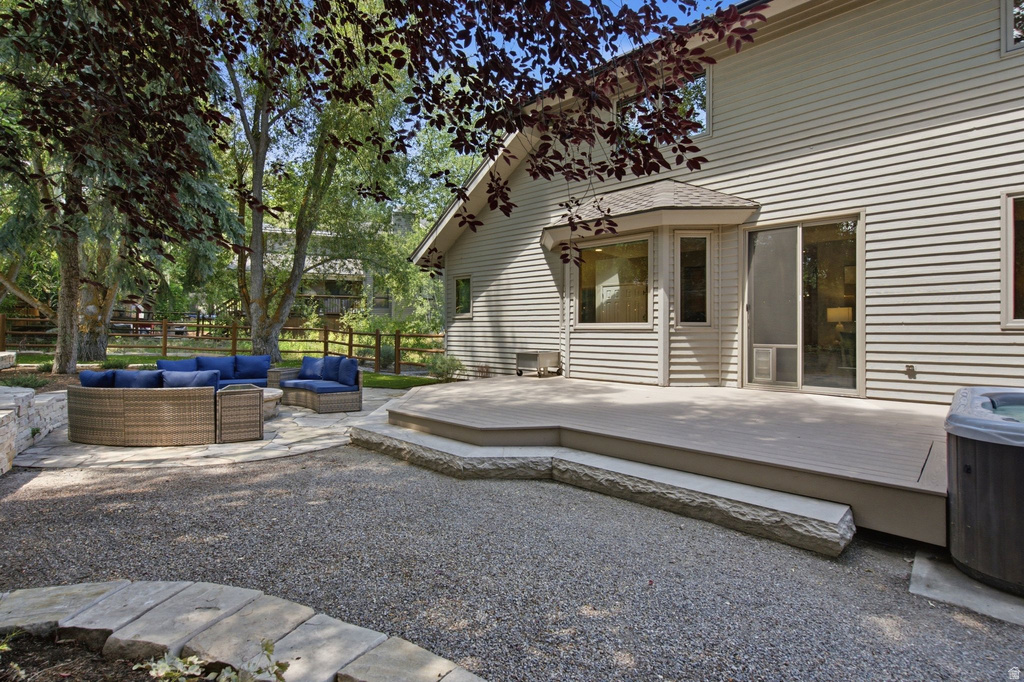 Expansive outdoor living area featuring a composite deck, a stone patio, and a gravel ground cover