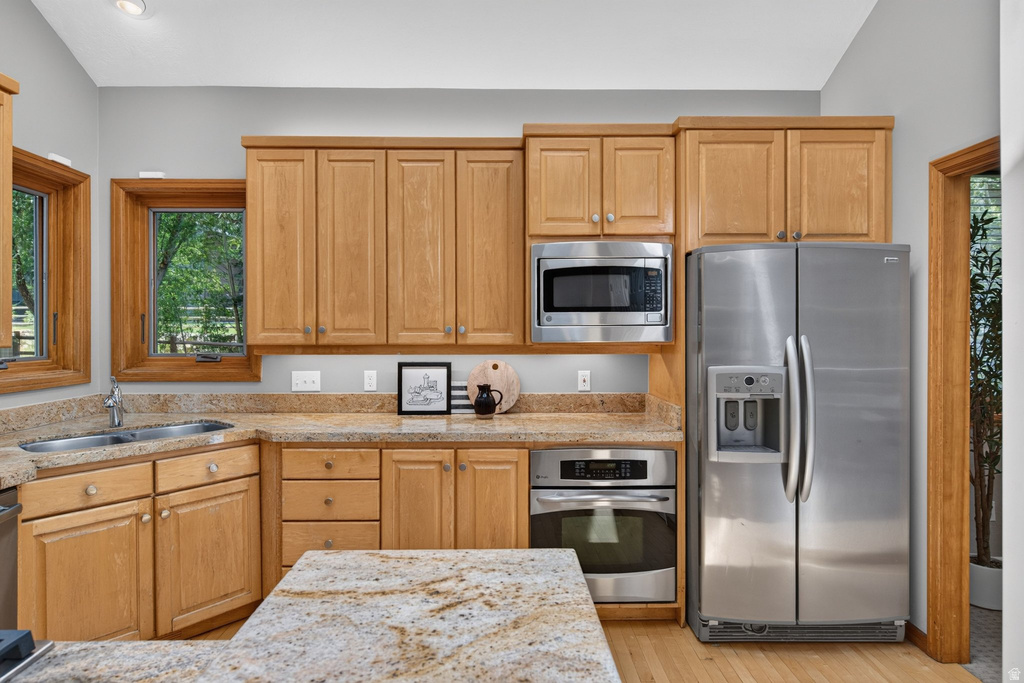 Kitchen featuring wood cabinetry, light-toned countertops, a stainless steel side-by-side refrigerator, and a built-in stainless steel microwave and oven