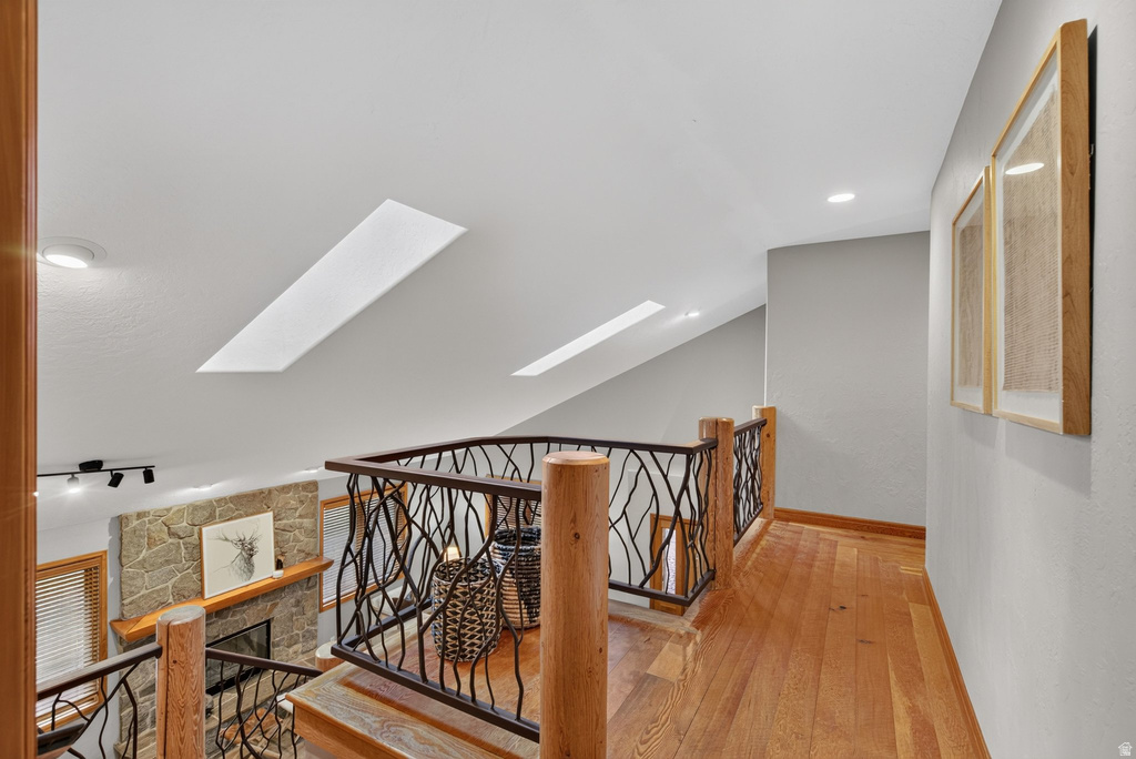 Upper-level hallway with wood-finish flooring, custom ironwork railing, and two skylights