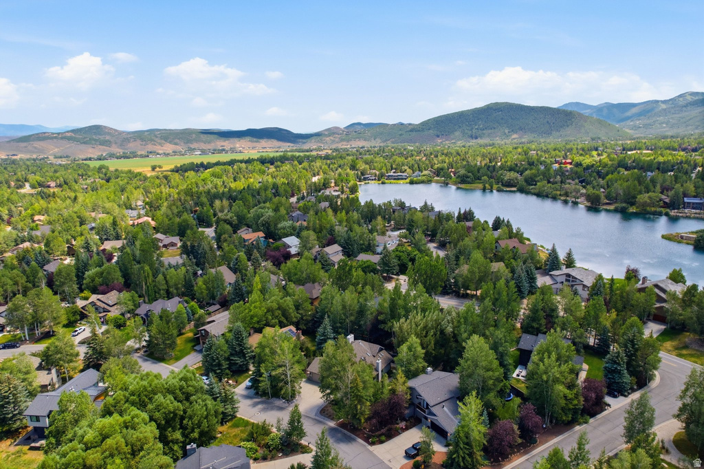 Tree-lined residential area featuring a prominent lake and surrounding mountains