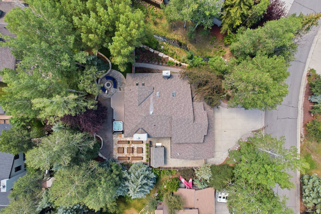 Expansive property featuring mature trees, multi-level landscaping, a circular stone patio with a built-in fire pit, a hot tub, and raised garden beds