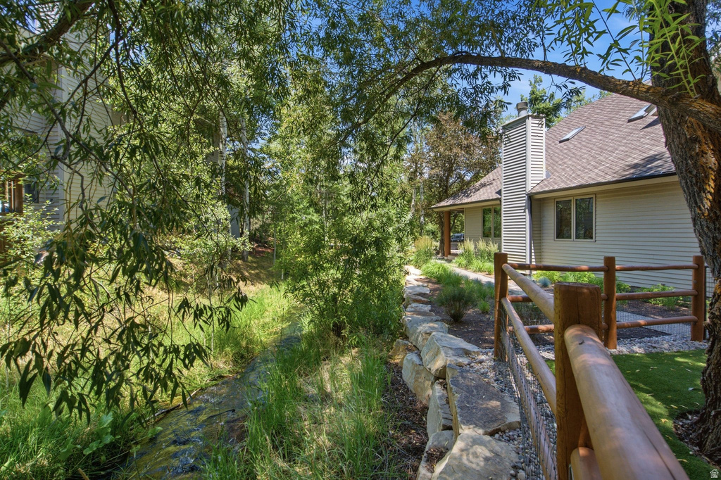 Expansive outdoor area featuring a natural stream, a rustic wooden fence, and a stone retaining wall