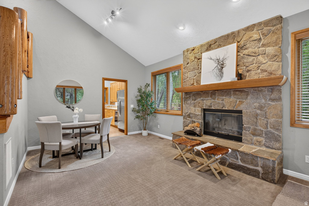Vaulted ceilings enhance this living space featuring a floor-to-ceiling stone fireplace with a wood mantle