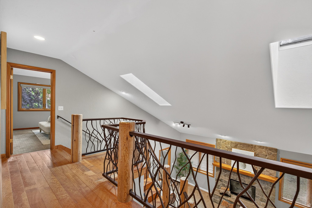 Upper-level hallway with wood-finish flooring and a decorative metal and wood railing