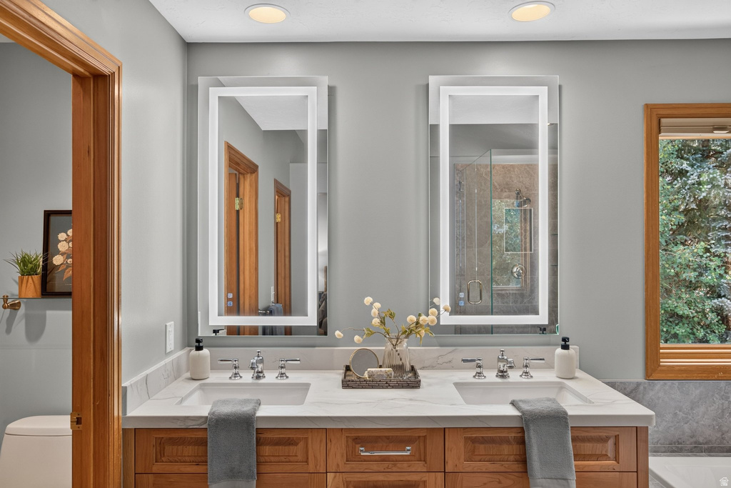 Double vanity with wood-finish cabinetry, integrated sinks, and polished chrome fixtures