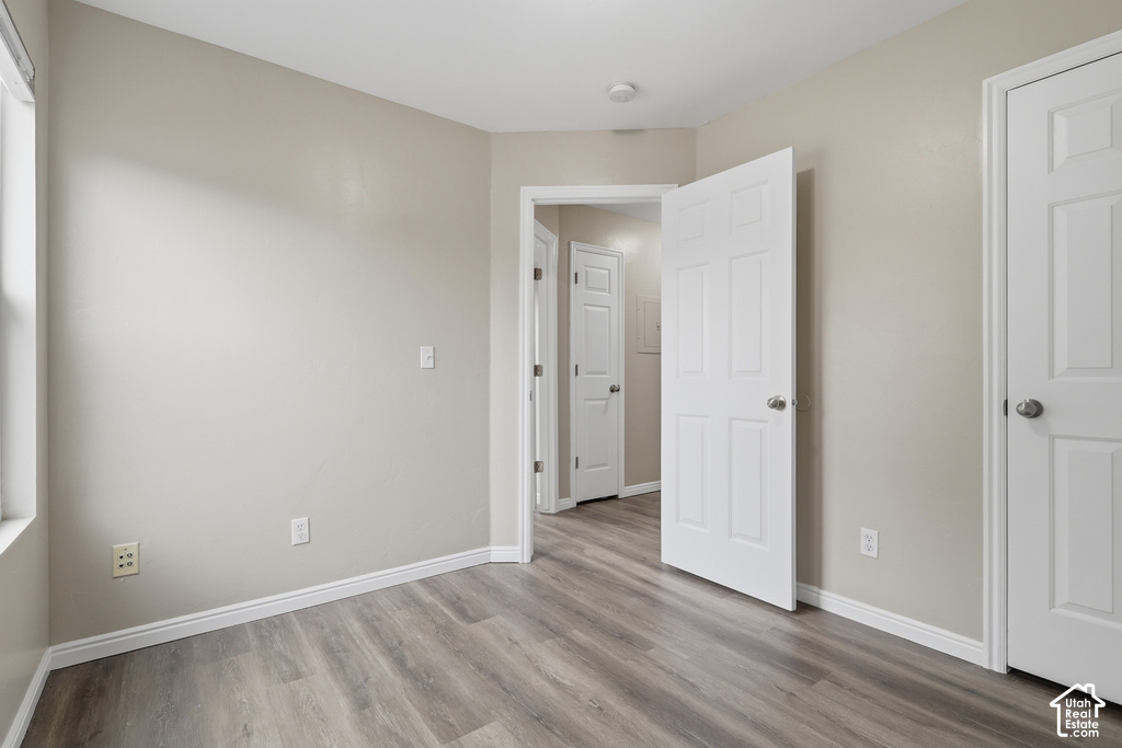 Interior room featuring wood-finish flooring, light neutral wall paint, white baseboards, and white paneled doors