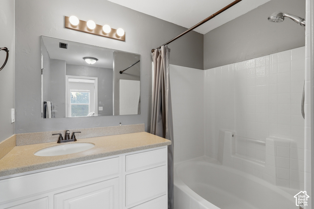 Bathroom featuring a white vanity with an integrated sink, a speckled countertop, and a large wall-mounted mirror