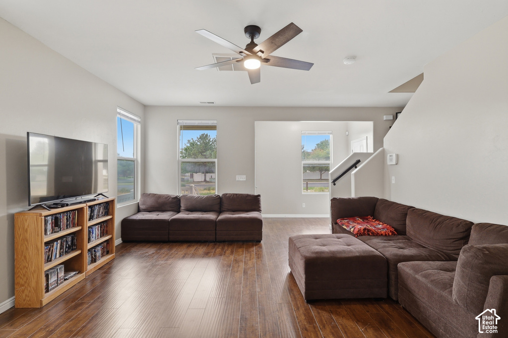 Spacious living area featuring wood-finish flooring, light neutral wall tones, and multiple windows