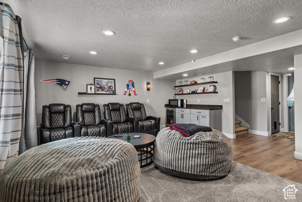 Entertainment space featuring recessed lighting, a built-in wet bar with cabinetry and solid surface countertop, wood-finish flooring, and a carpeted area
