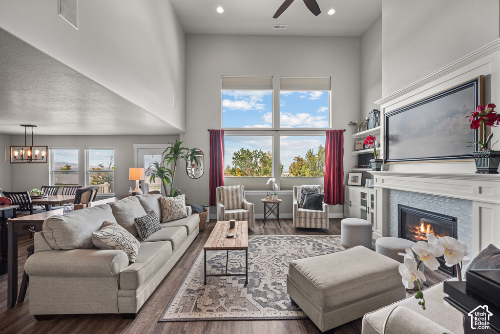 Open-concept living area with soaring ceilings, wood-finish flooring, a contemporary fireplace with a tiled surround, and extensive windowing