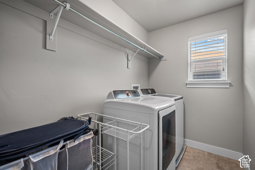 Utility space featuring a window with blinds, upper shelving with a hanging rod, and light-toned flooring
