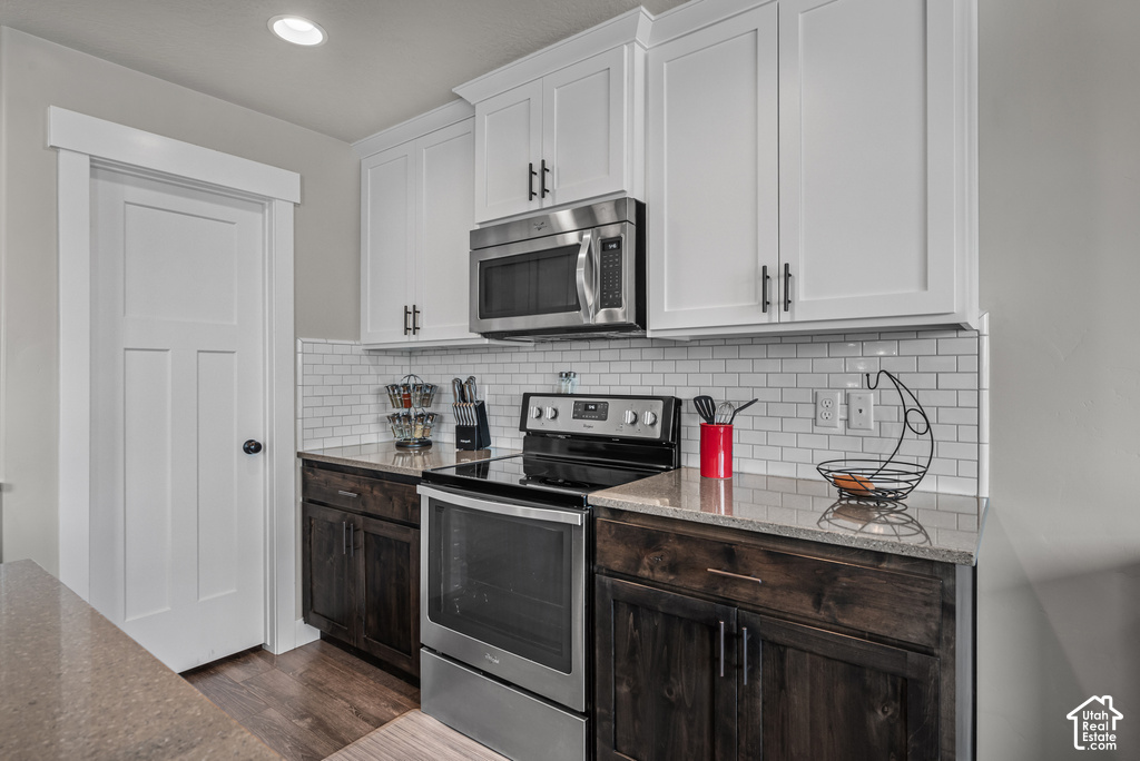 Kitchen featuring white shaker-style upper cabinetry, dark wood-finish lower cabinetry, and stainless steel appliances