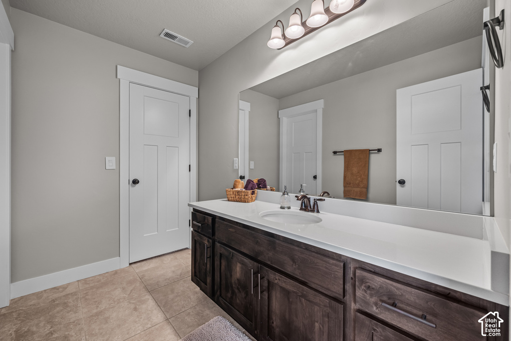 Vanity with a white countertop and integrated sink, dark wood-finish cabinetry, and bronze-finish hardware
