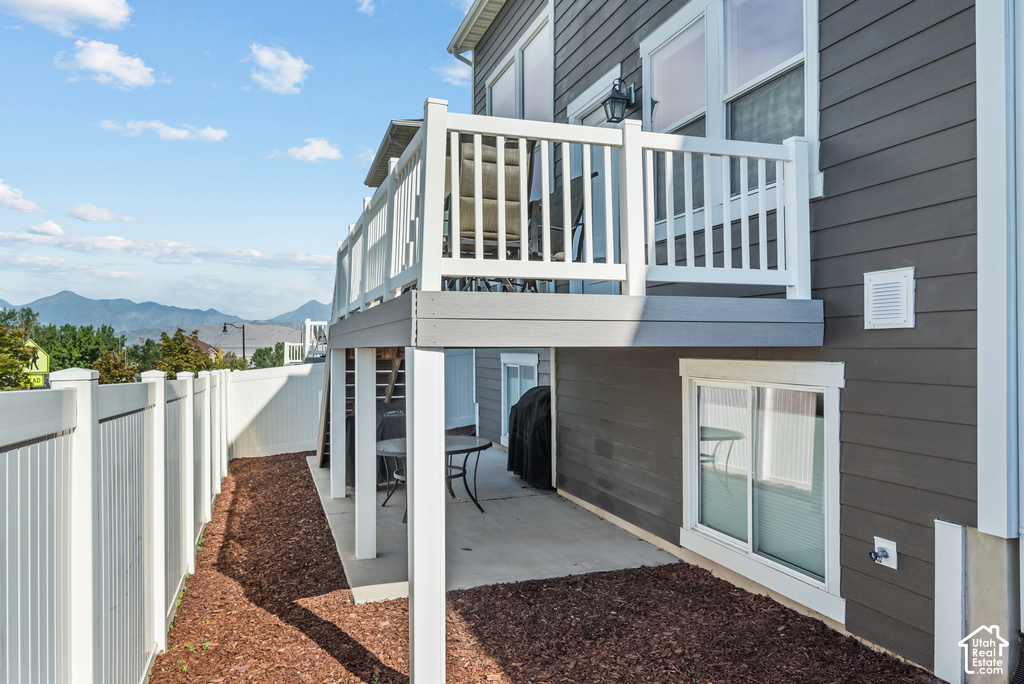 Upper-level balcony with white railing, lower-level patio, and dark gray horizontal siding