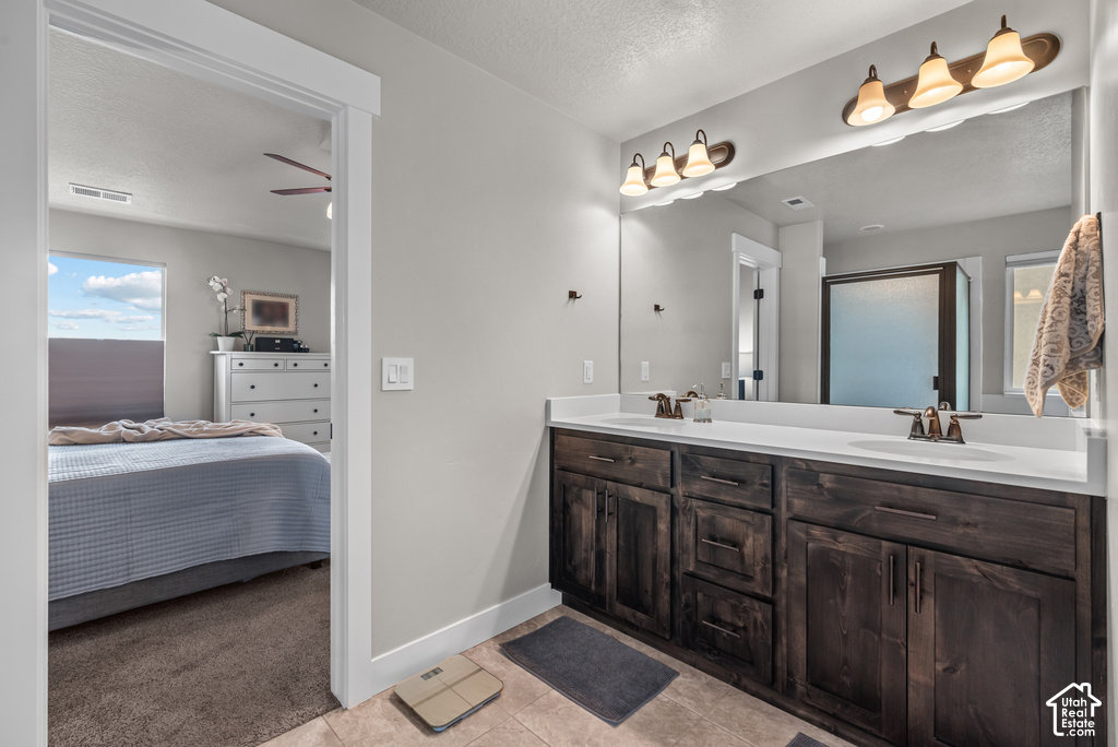 Dual vanity with dark wood-finish cabinetry, white countertops, and bronze-tone fixtures