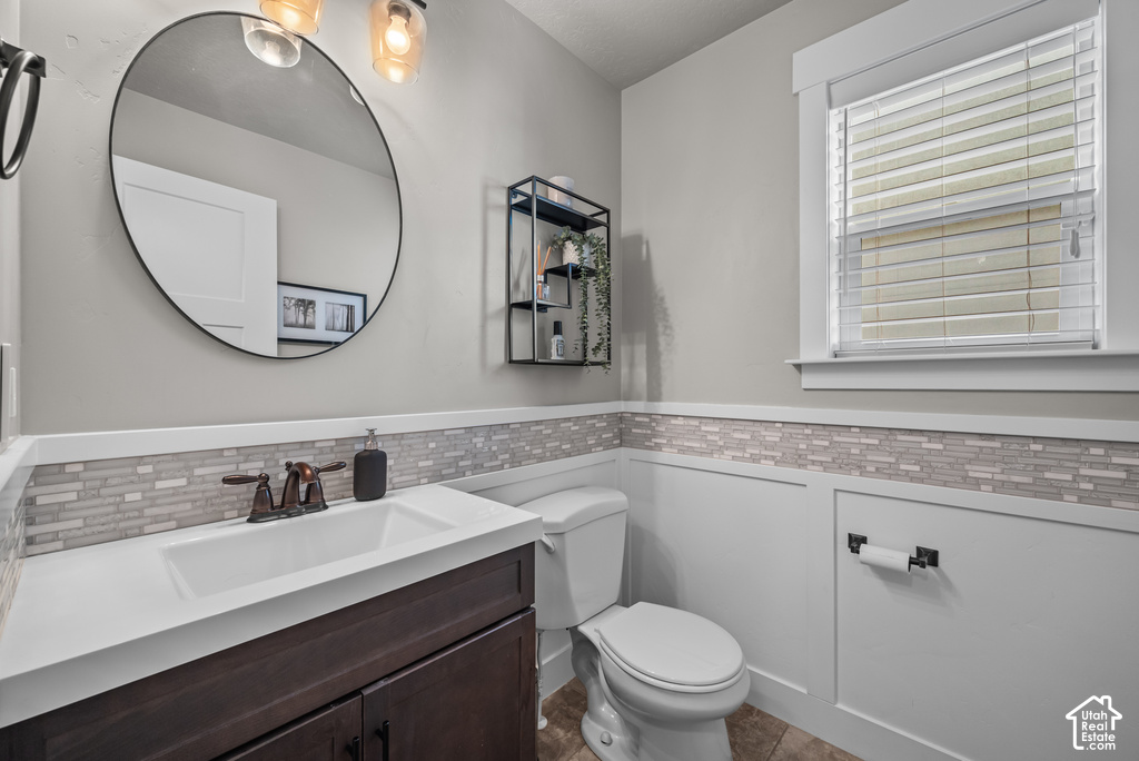 Bathroom featuring a dark wood-finish vanity with an integrated sink, white countertop, and mosaic tile backsplash