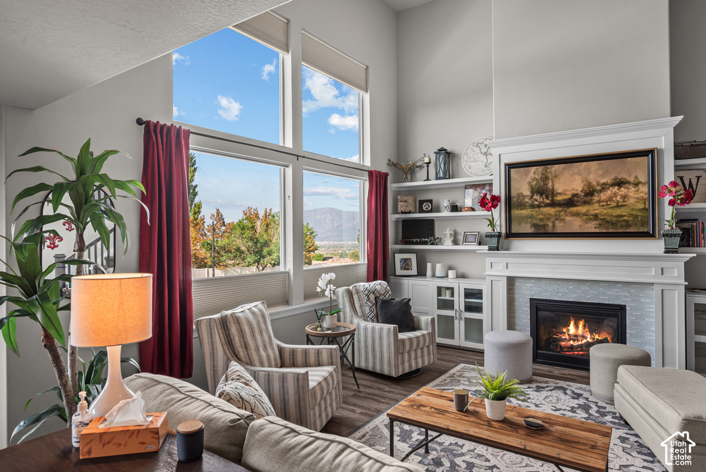 Spacious living area featuring large windows, vaulted ceilings, built-in shelving, a fireplace with a tile surround, and wood-finish flooring