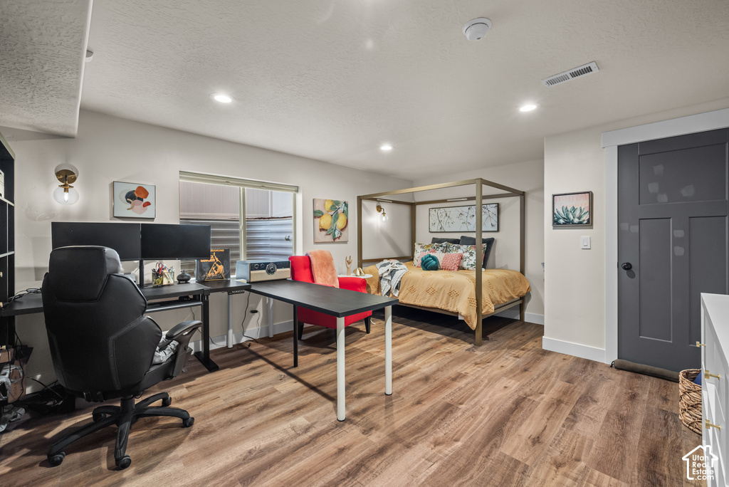 Open-concept room featuring wood-finish flooring, recessed lighting, and a dark-paneled door with white trim