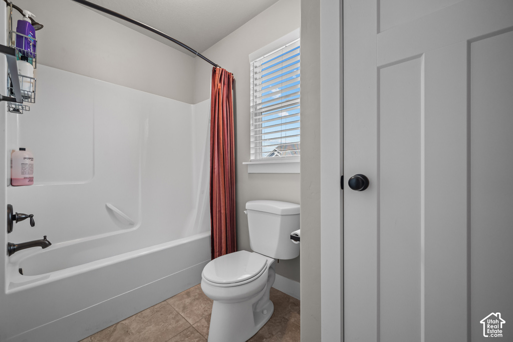 Bathroom featuring a combination shower and tub, tile flooring, and a window with blinds