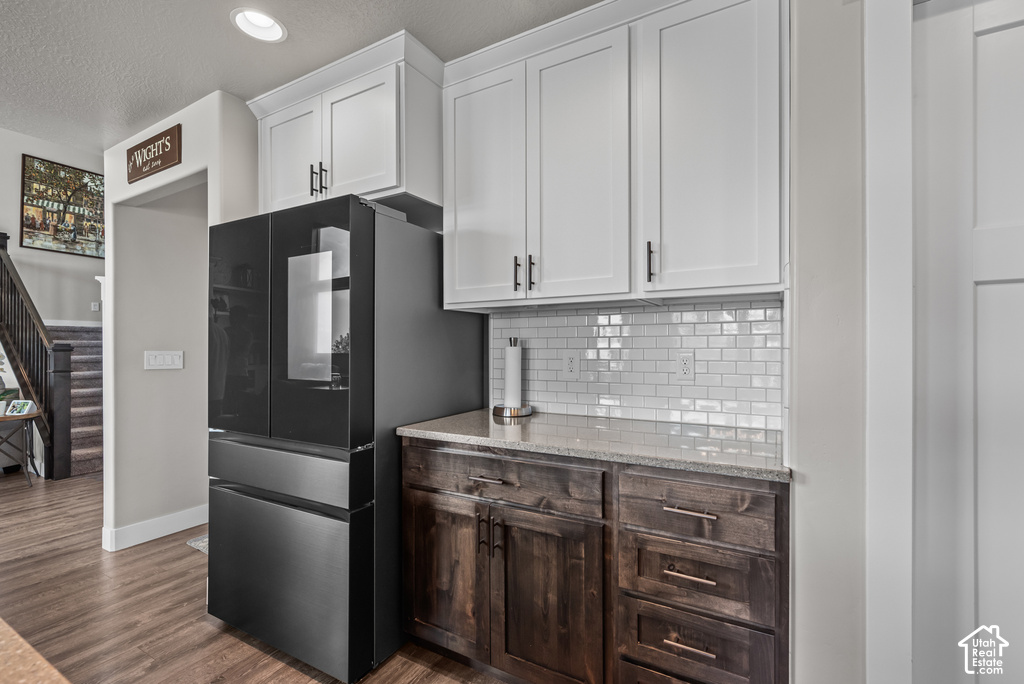 Kitchen area with a built-in refrigerator, white upper cabinetry, and dark wood-finish lower cabinetry
