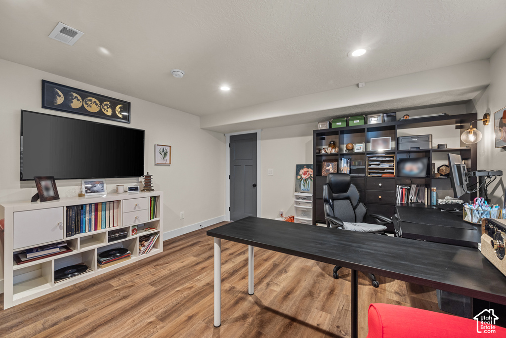Versatile room featuring wood-finish flooring, recessed lighting, and a built-in shelving unit