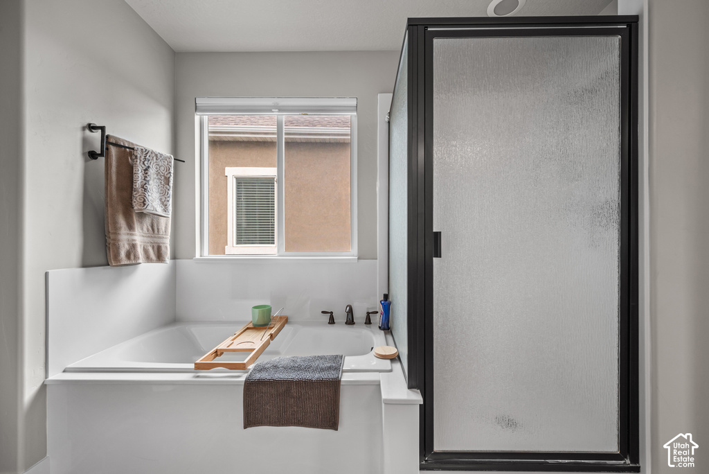 Contemporary bathroom featuring a built-in soaking tub with a tiled surround, a sliding window, and a separate shower enclosure with a dark-framed frosted glass door