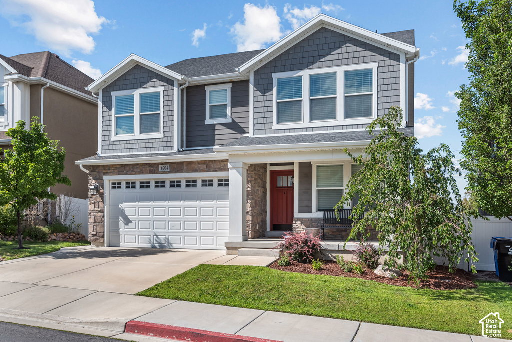 Contemporary two-story exterior featuring gray siding, stone accents, a red front door, an attached two-car garage, and a concrete driveway