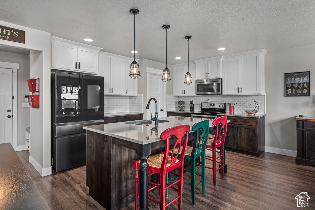 Kitchen featuring wood-finish flooring, white upper cabinetry, dark lower cabinetry, and a subway tile backsplash