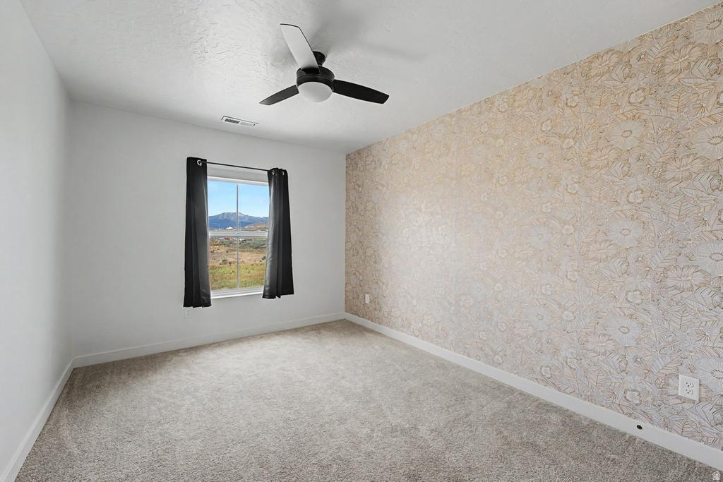 Room featuring a patterned accent wall, white painted walls, and light-colored carpet flooring
