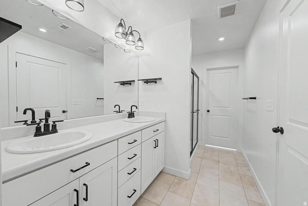 Double vanity with matte black fixtures and hardware, white cabinetry, and a large wall-mounted mirror