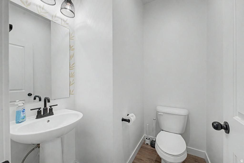Pedestal sink with matte black faucet, wall-mounted mirror, and decorative wallpaper accent