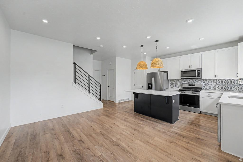 Open-concept living space featuring wood-finish flooring, recessed lighting, and a modern kitchen