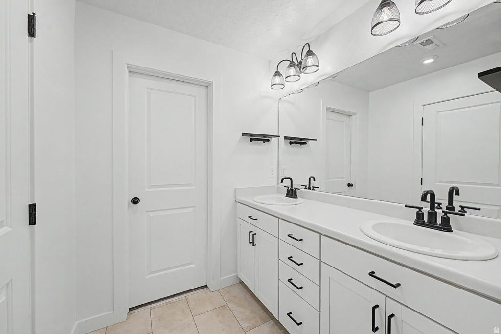 Double vanity with white cabinetry and integrated sinks, matte black hardware, full-width mirror, and a three-light fixture