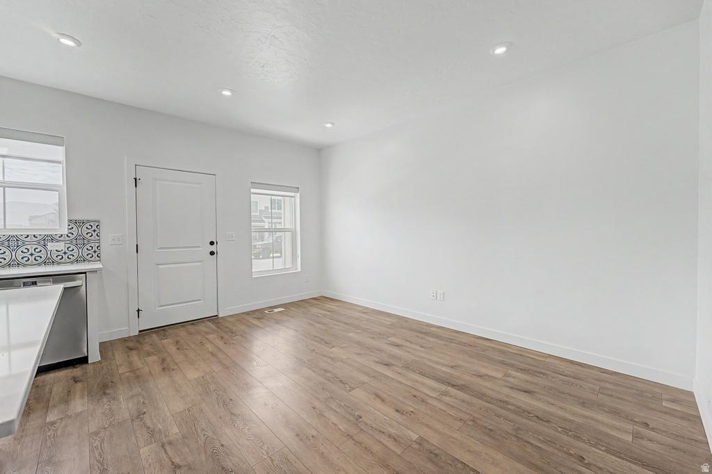 Spacious interior featuring wood-finish flooring, recessed lighting, and a white paneled door