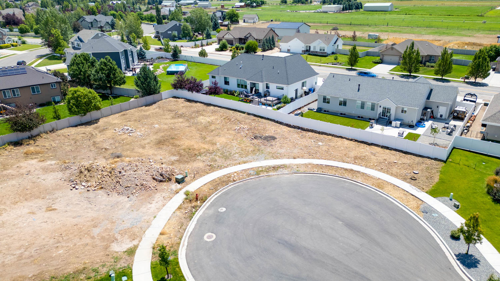 Residential building lot featuring direct street access, a curved sidewalk, and a surrounding privacy fence