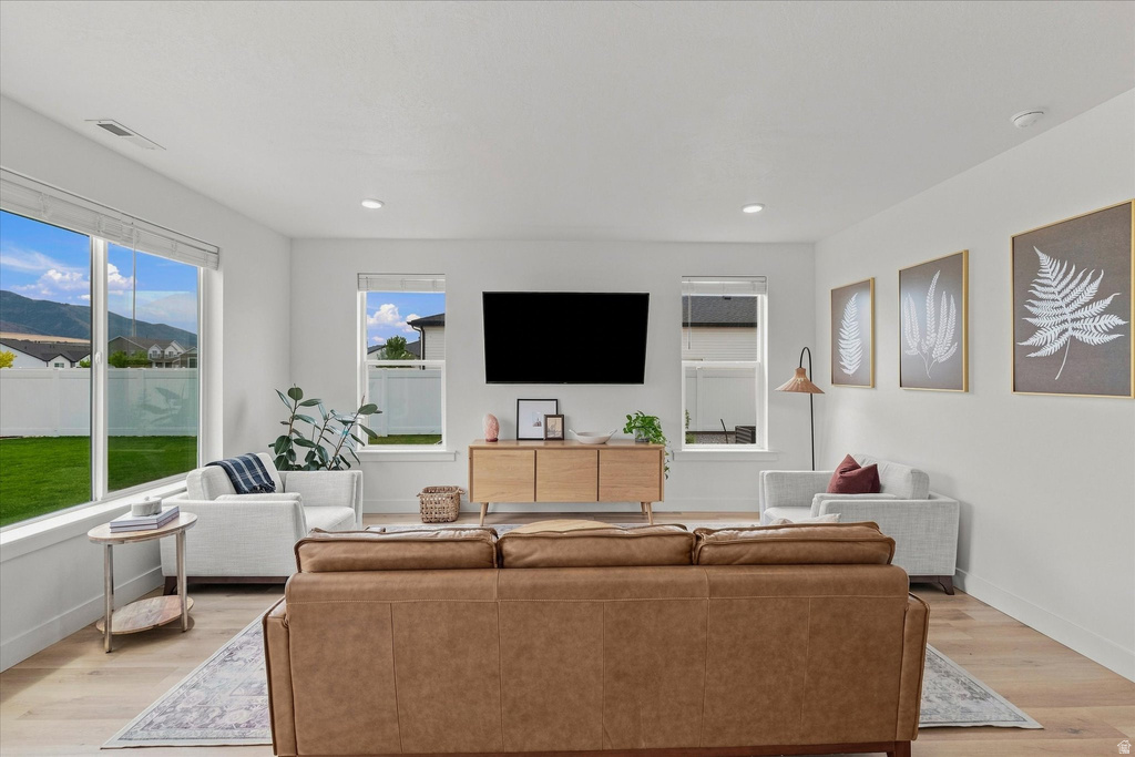 Bright living space featuring expansive windows, recessed lighting, wood-finish flooring, and crisp white walls