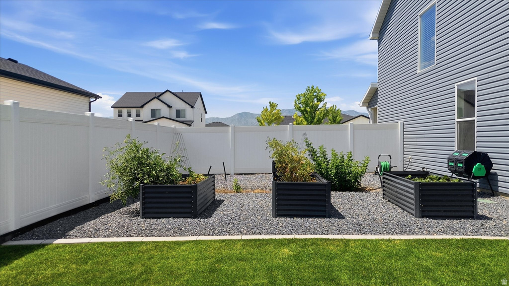 Landscaped backyard featuring three raised garden beds, a gravel ground cover, and a manicured lawn