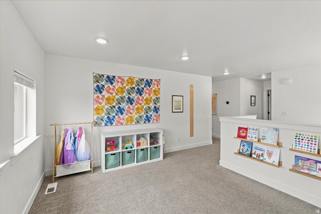 Carpeted interior area with recessed lighting, a window with white trim, and white walls