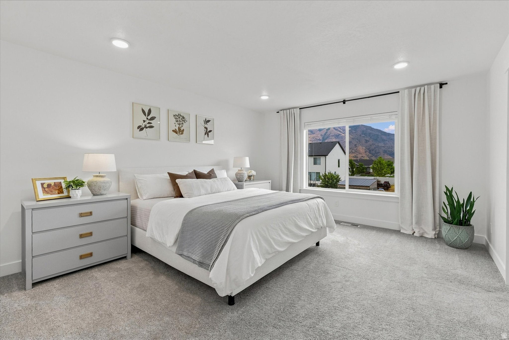 Spacious carpeted room featuring a large window with mountain scenery, recessed lighting, and white walls
