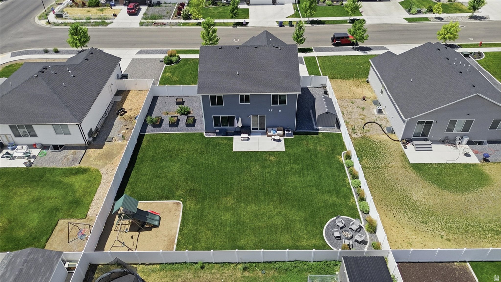 Expansive backyard featuring a large green lawn, concrete patio, and a dedicated fire pit area