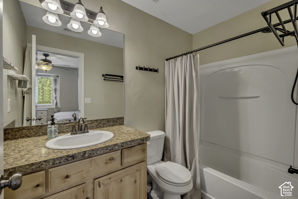 Bathroom featuring a vanity with a light wood-finish cabinet and a speckled countertop, a white drop-in sink with a bronze-finish faucet, and a wall-mounted mirror