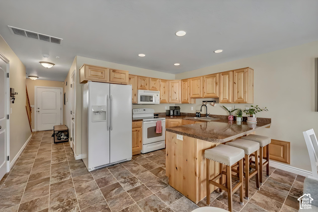 Kitchen featuring wood-finish cabinetry, granite-style countertops, white appliances, and a breakfast bar