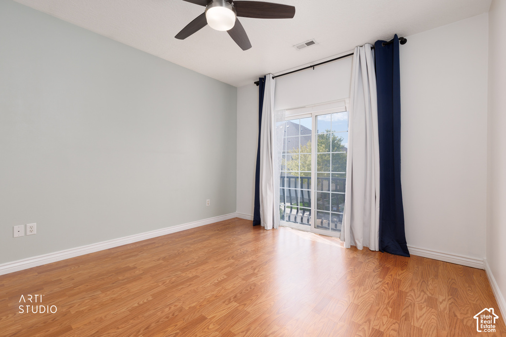 Spacious room featuring wood-finish flooring, a contemporary ceiling fan, and a sliding glass door leading to a private balcony