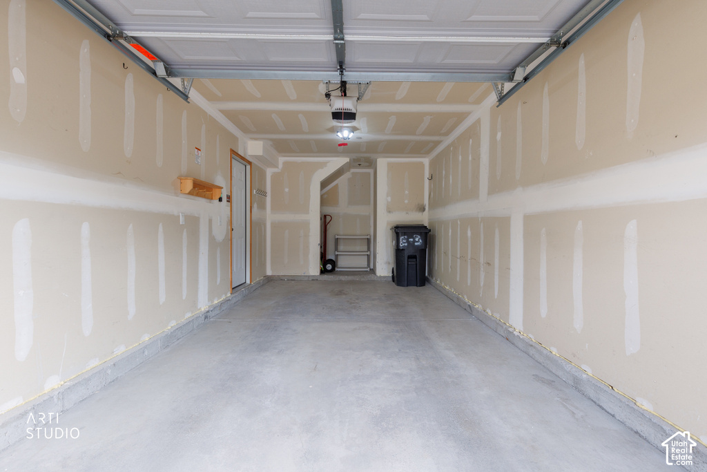Two-car garage featuring a concrete floor, automatic garage door opener, and interior access door