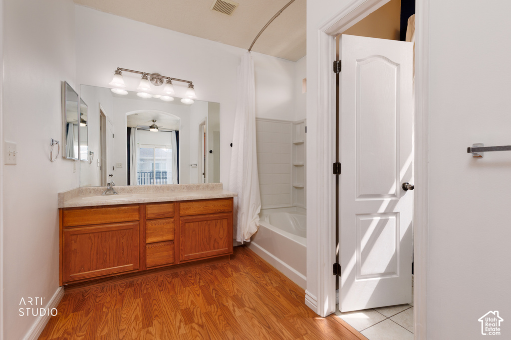 Bathroom featuring a wood-finish vanity with a light-colored countertop and an integrated sink