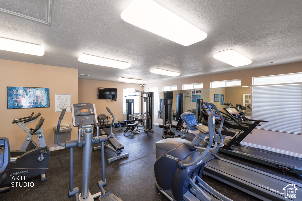Dedicated fitness center featuring multiple cardio machines, weight training equipment, mirrored walls, and mounted televisions